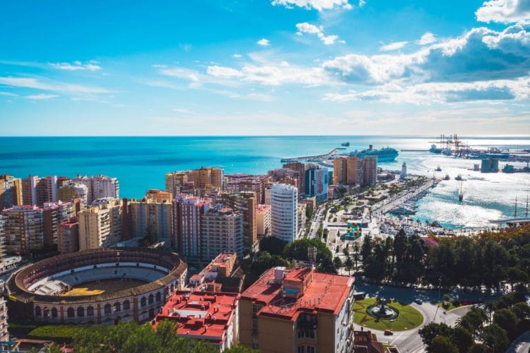 Vista panorámica desde el mirador de málaga con la plaza de toros, edificios altos y el puerto al fondo.