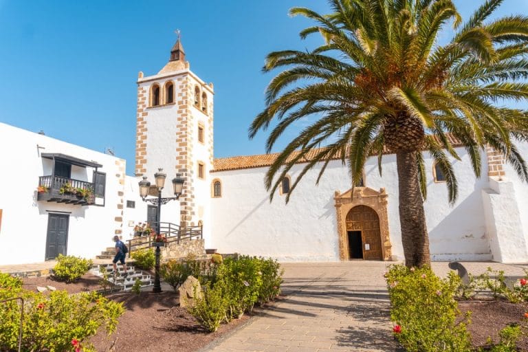 Fachada principal de la Iglesia de Santa María de Betancuria con palmera y cielo despejado en Fuerteventura.