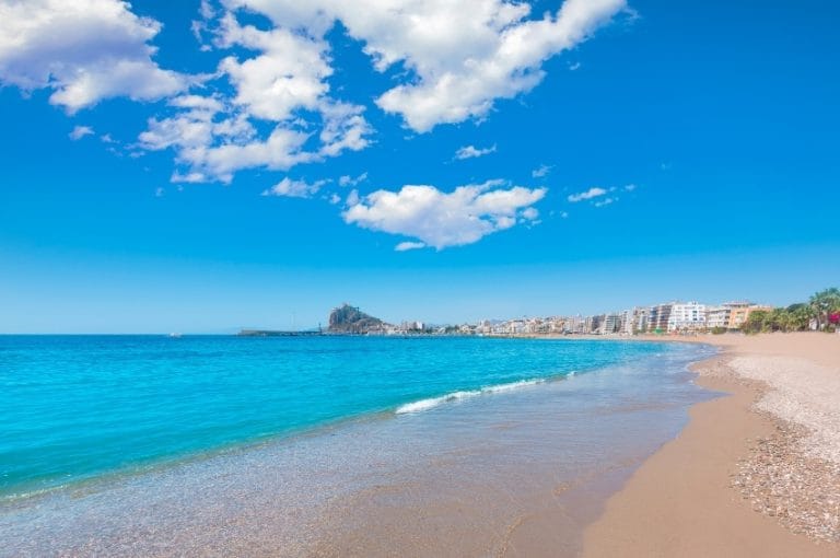 Vista panorámica de la playa de Águilas en Murcia con arena dorada, mar azul y edificios al fondo bajo cielo despejado con nubes