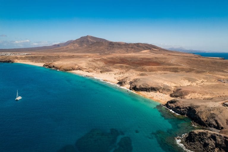 Vista aérea de la playa de Papagayo en Lanzarote con aguas turquesas y paisaje volcánico al fondo