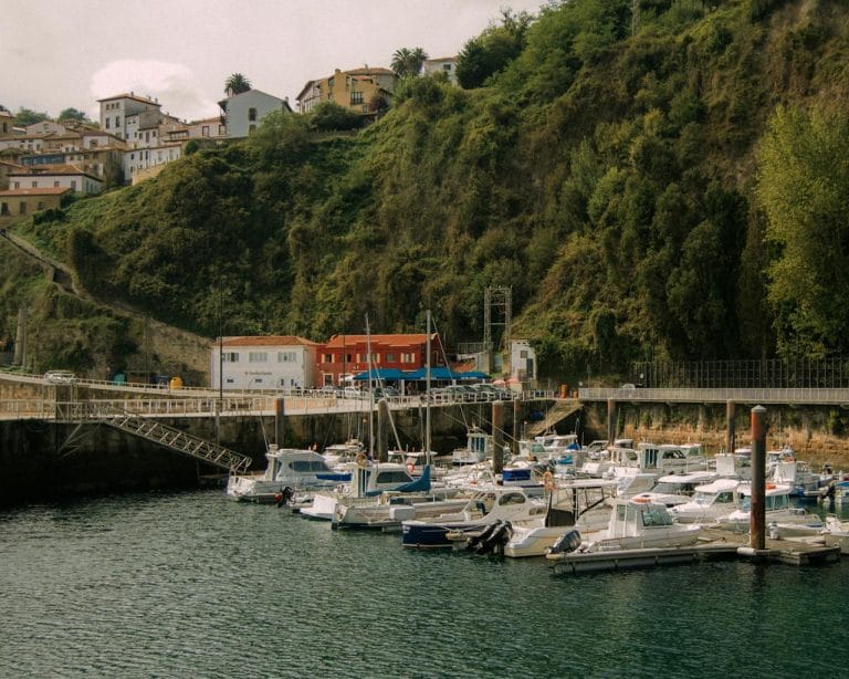 Puerto de Lastres en Asturias con barcos atracados y casas en la ladera.