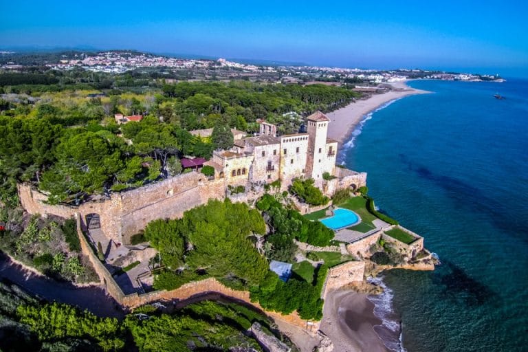 Vista aérea del castillo de Tamarit rodeado de bosque y junto a la playa en la Costa Dorada