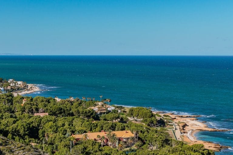Vista aérea de la costa de Dénia (Alicante) con vegetación mediterránea, casas junto al mar y aguas del Mediterráneo