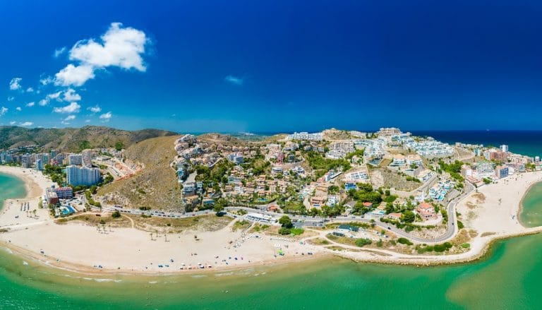 Vista aérea de Cullera con sus playas de arena dorada, urbanizaciones y colinas junto al mar Mediterráneo