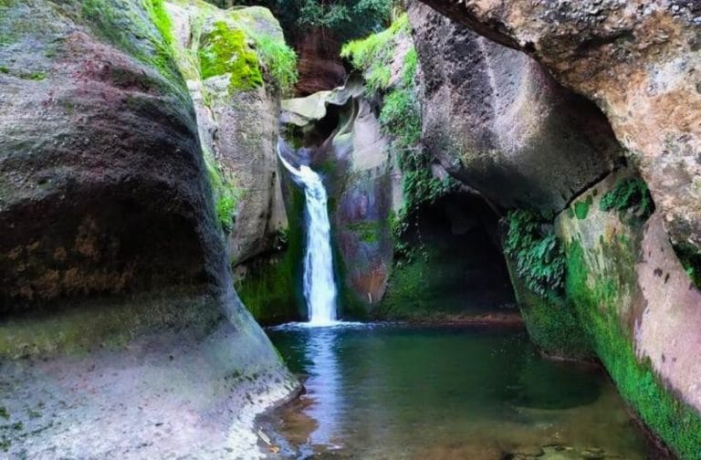 Cascada del Gorg de la Mola en Barcelona rodeada de paredes rocosas y vegetación verde