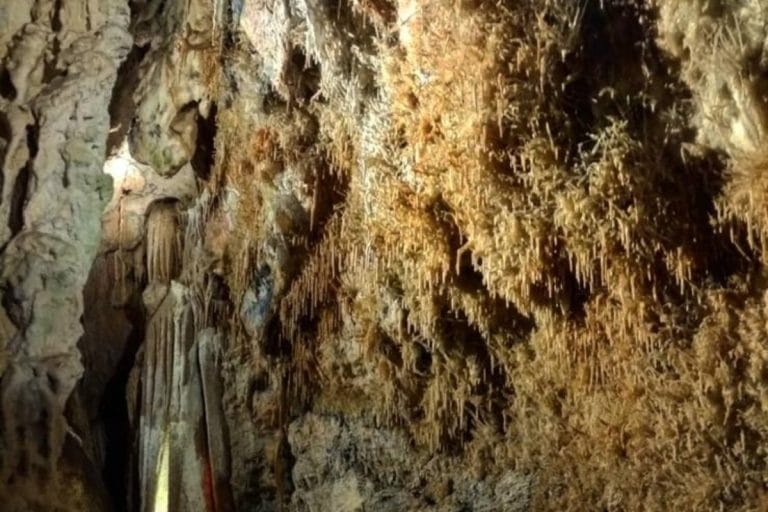 Interior de la Gruta de Cristal en Molinos, mostrando numerosas formaciones de estalactitas de color ocre colgando del techo de la cueva.