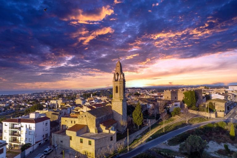 Vista aérea del centro histórico de Creixell al atardecer, con la iglesia y el castillo medieval