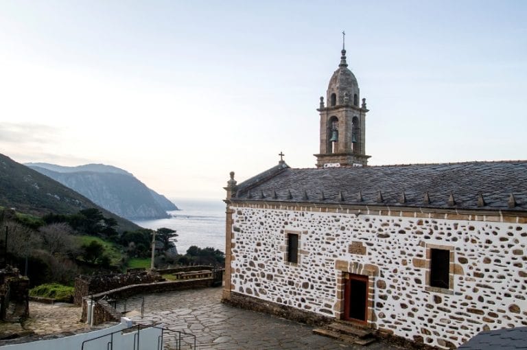 Iglesia de San Andrés de Teixido con vistas al mar y acantilados de la costa de Galicia al fondo.