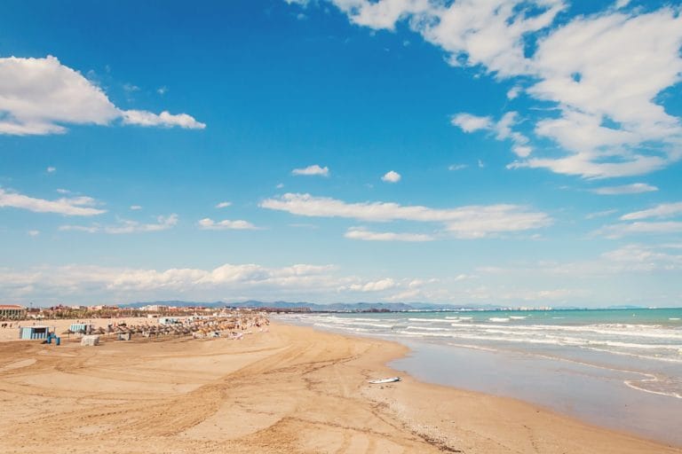Vista panorámica de la Playa de la Malvarrosa en Valencia con sombrillas y cielo despejado