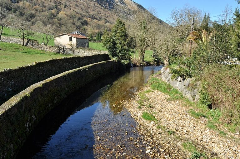 Pequeño río en Arredondo, Cantabria, rodeado de vegetación y montañas en un entorno rural