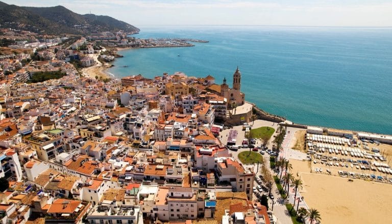 Panorámica aérea de Sitges con la iglesia de Sant Bartomeu y Santa Tecla junto al paseo marítimo y la playa