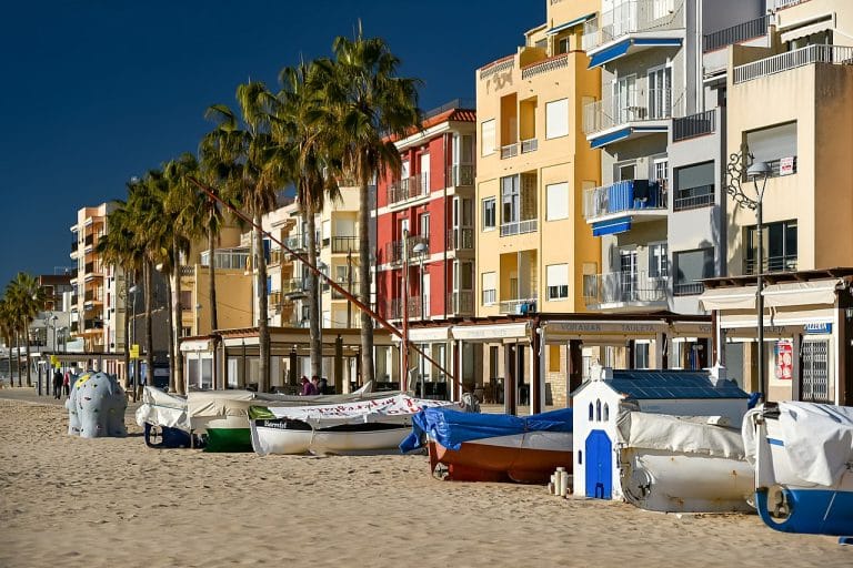 Barcos en la arena frente a edificios de colores en el paseo marítimo de Torredembarra